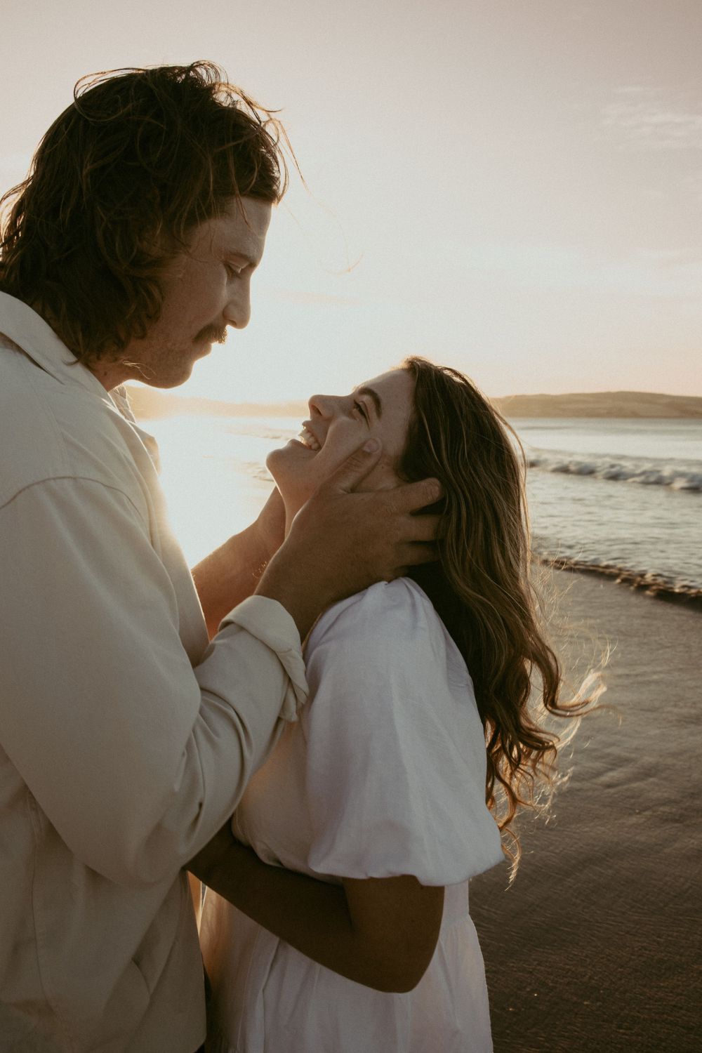 A tender embrace captured against the backdrop of a sunset beach.