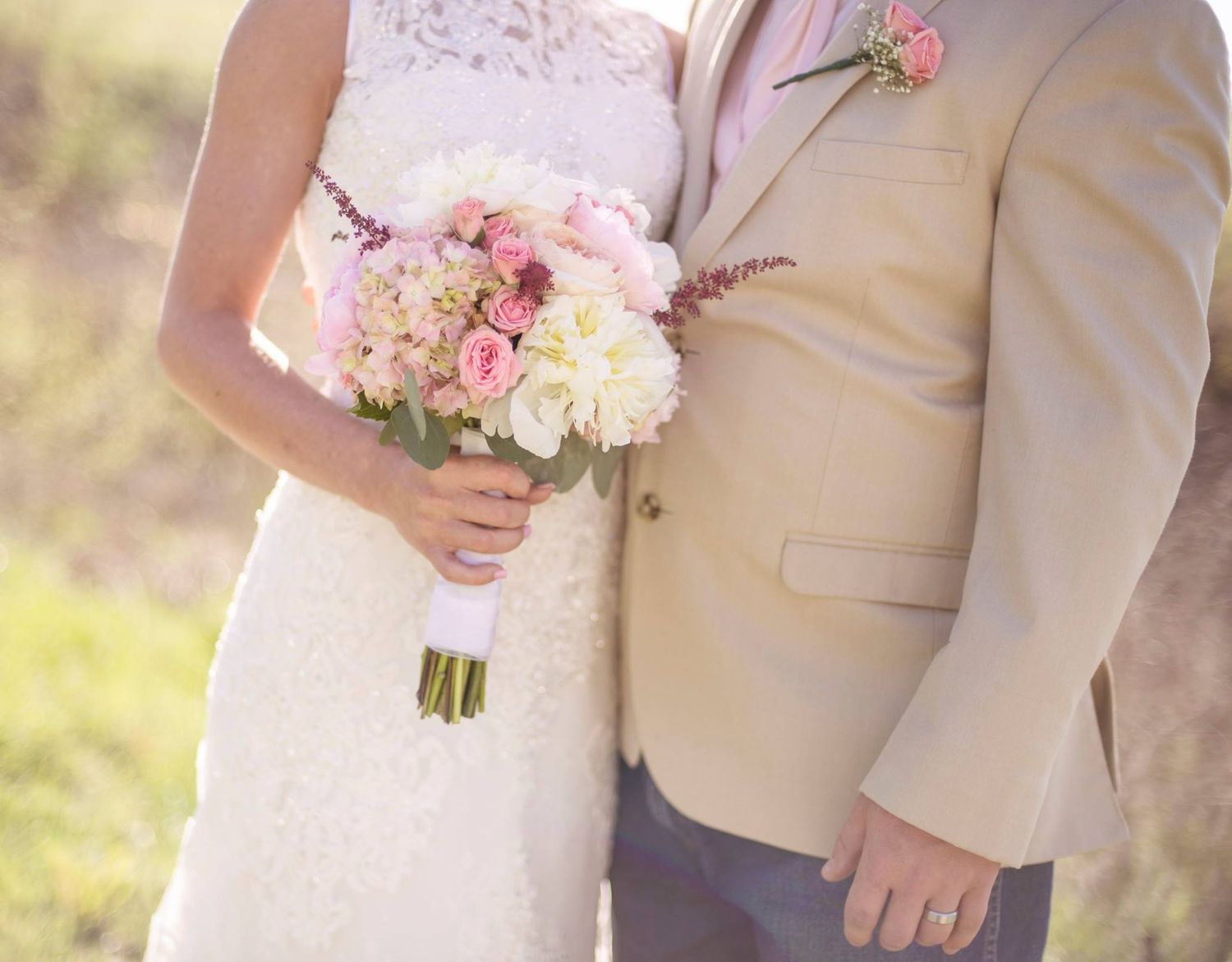 Wedding party holding pink and white floral bouquets in formal attire.