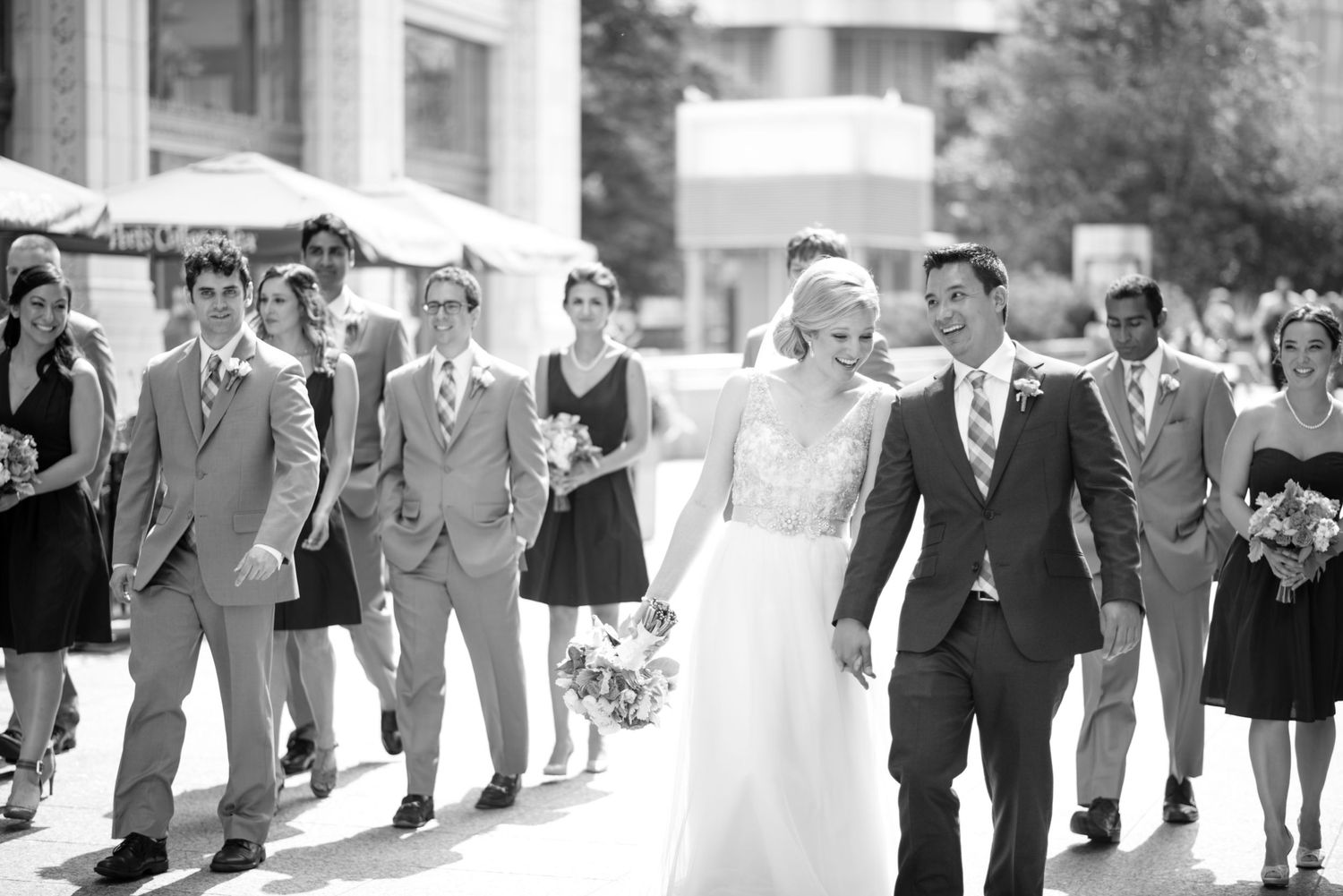 Wedding party walking and laughing together outdoors in formal attire.