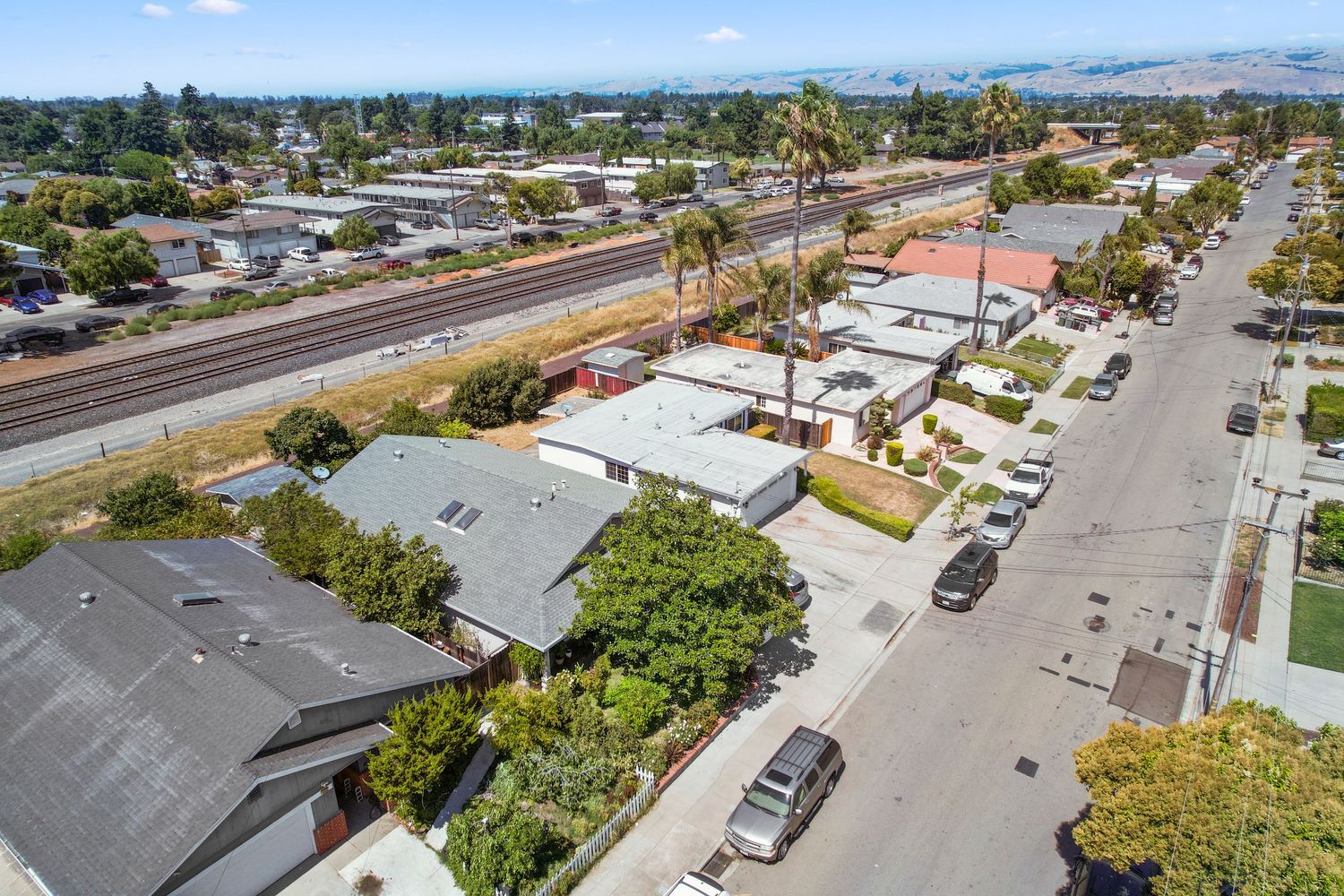 Panoramic aerial view of suburban development with streets and buildings against mountain backdrop.
