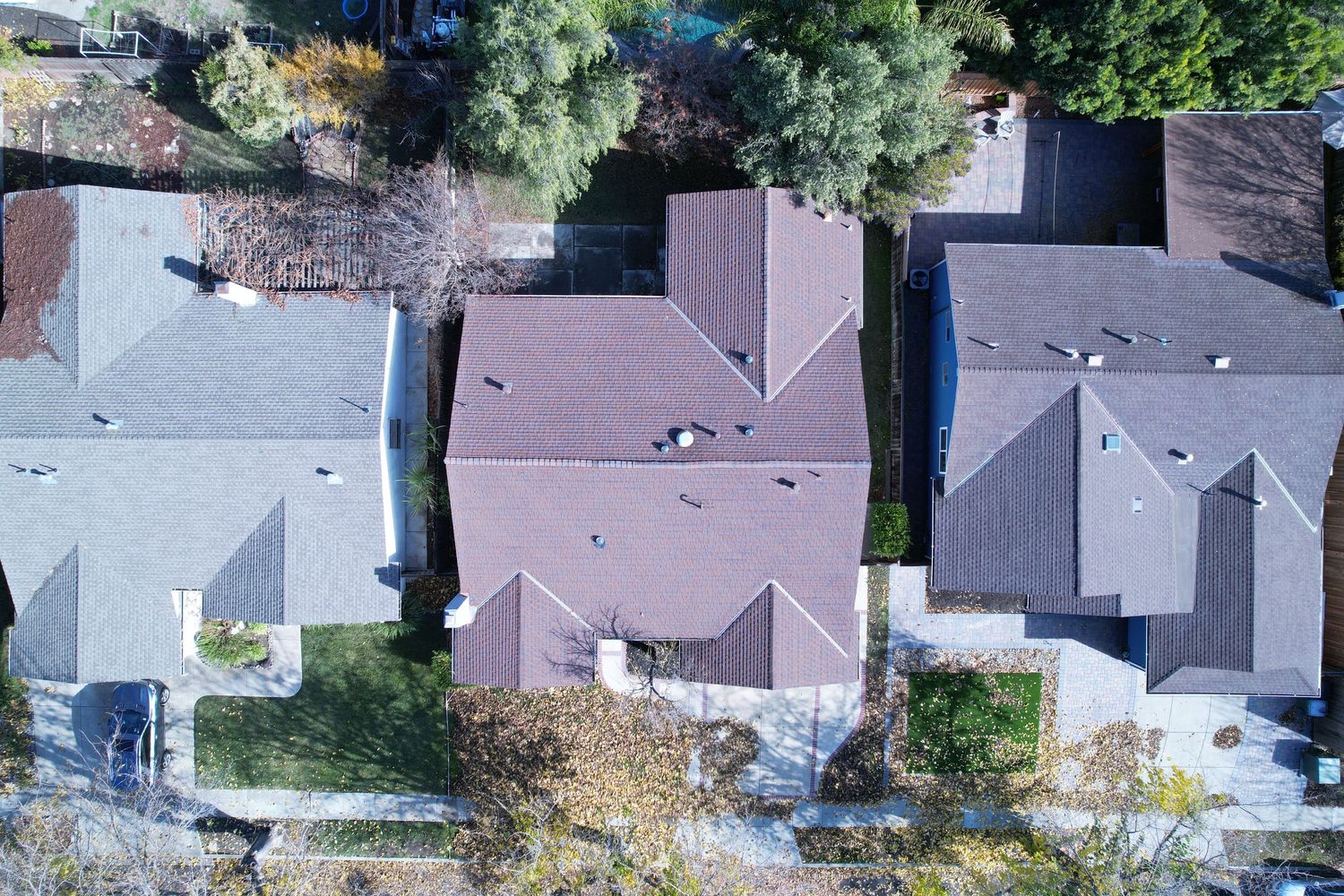 Overhead drone view of residential neighborhood showing rooftops and tree-lined streets.