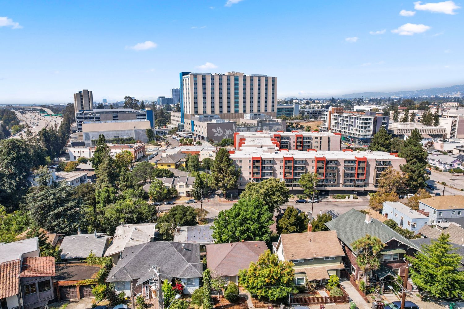Aerial cityscape showing mix of urban buildings, residential areas and development against blue sky.