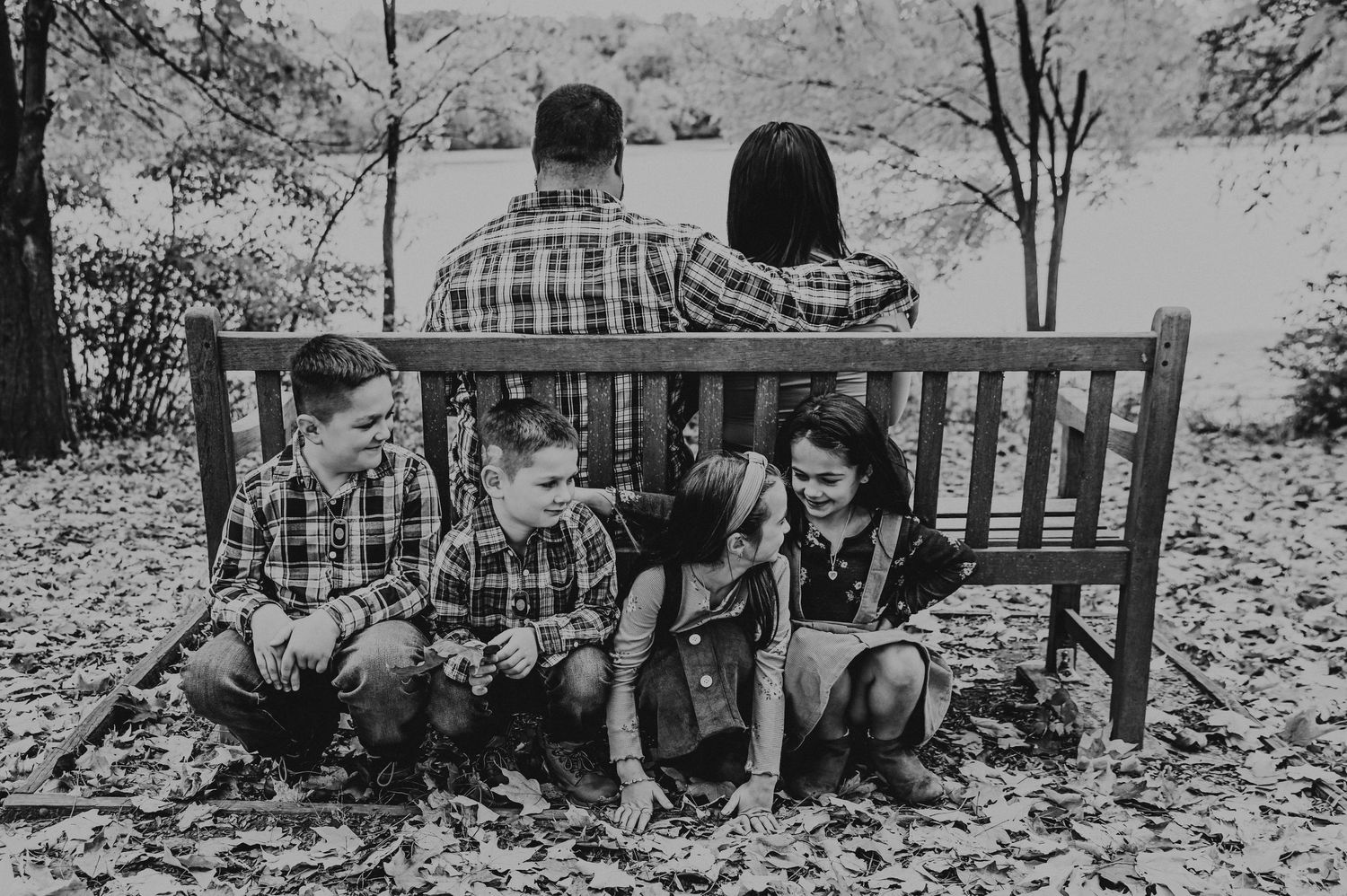 Black and white panoramic view of people sitting on a bench in a natural outdoor setting.