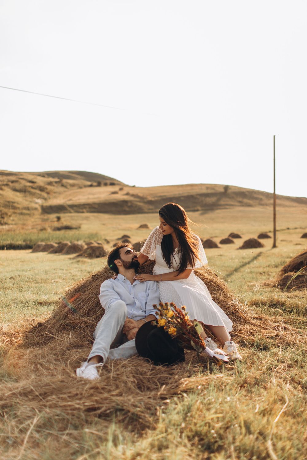 Intimate moment captured on rustic farmland with golden hills in background.