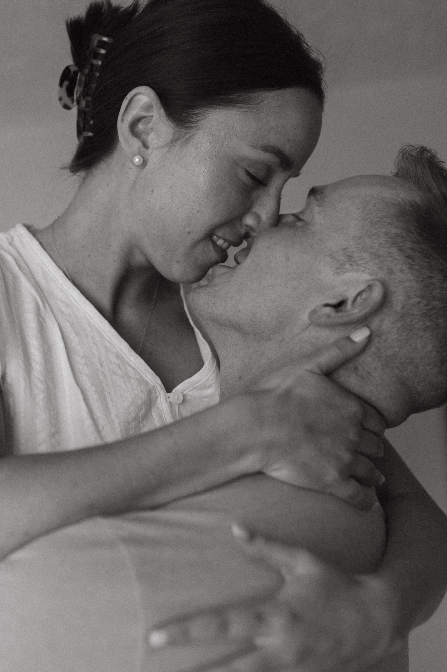 Black and white intimate portrait of a tender romantic embrace between a couple in white.