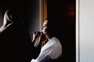 Dramatic silhouette of preparing for wedding in dark room with window light.