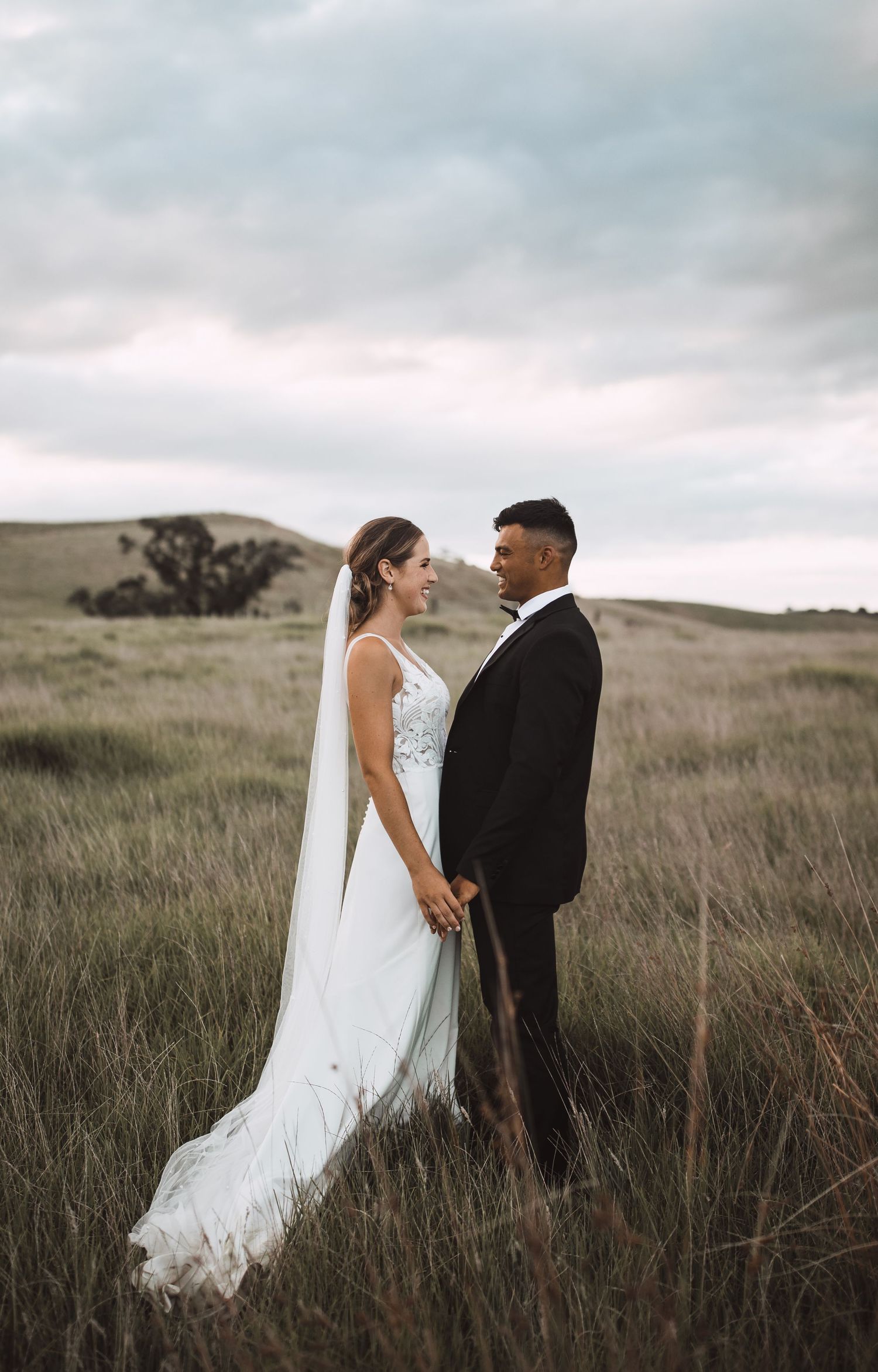 Romantic wedding portraits in a golden field with dramatic cloudy skies.