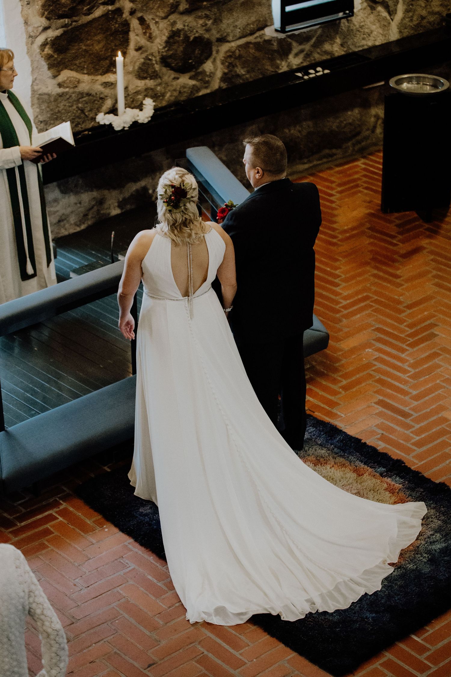 A bride in an elegant flowing white dress stands at the altar during a wedding ceremony.
