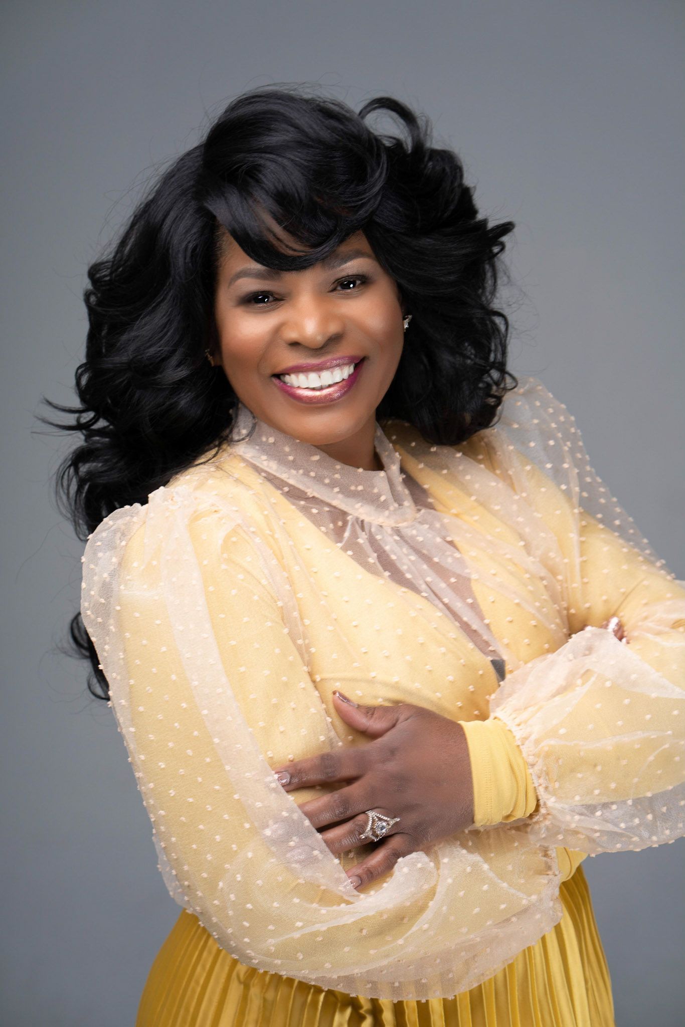 Studio portraits featuring yellow dress with pearl embellishments against gray background.
