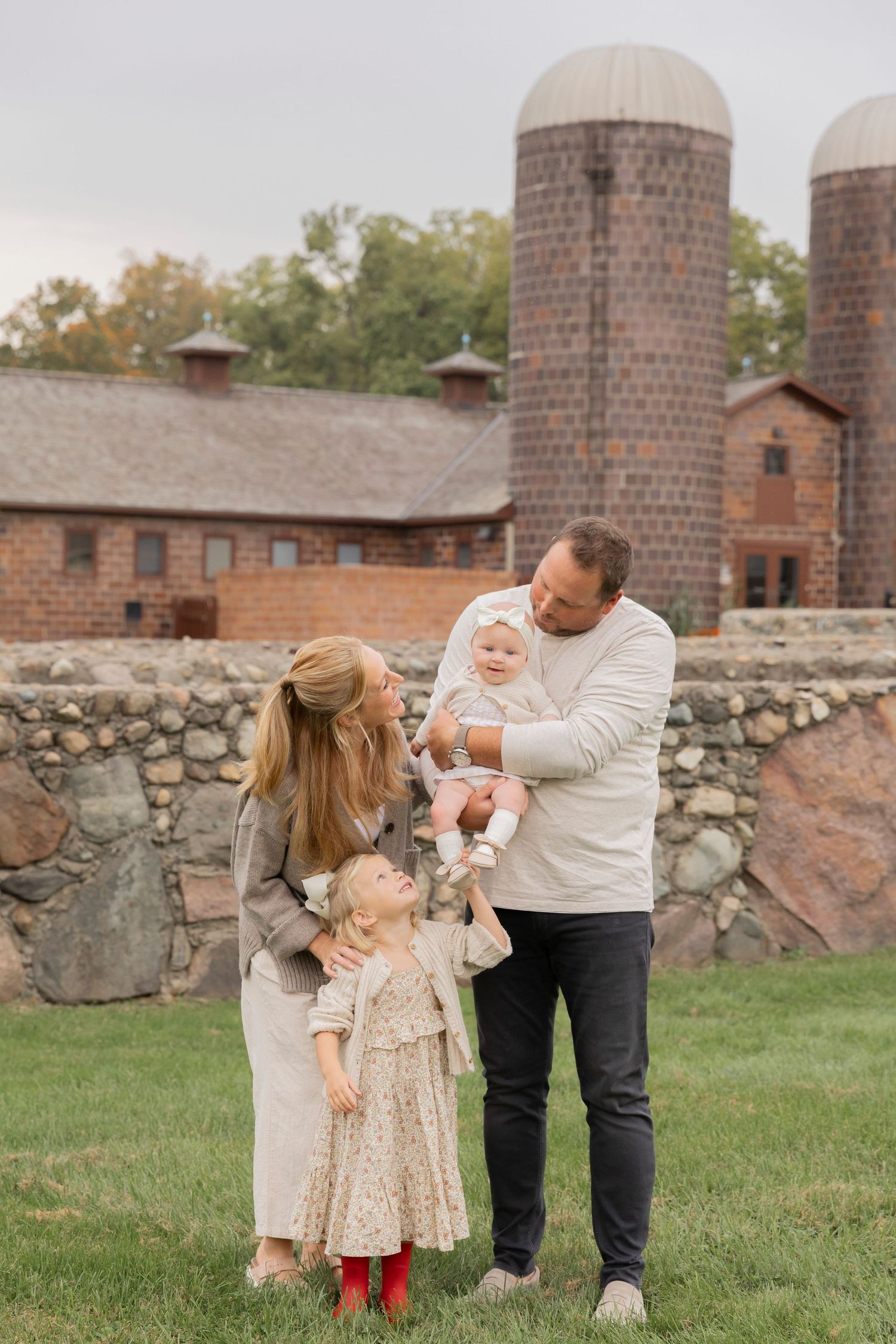 family of four standing in front of van hoses farm playing with each other