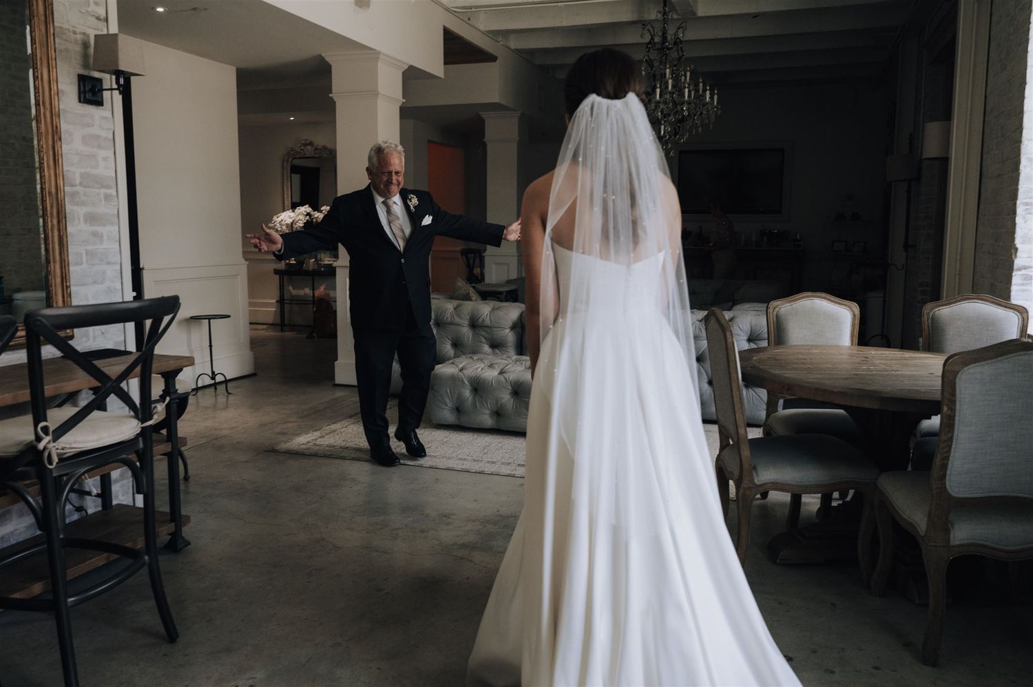 Wedding first look moment captured in modern industrial space with gray furniture.
