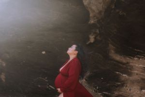 A couple embraces near dark rocky cliffs during a beach photoshoot.