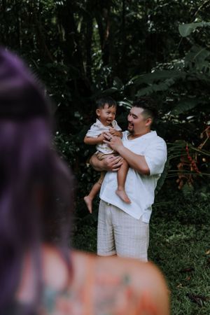 A tender family moment captured against a backdrop of lush greenery.