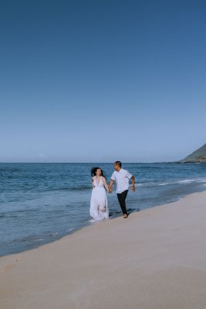 A distant view of a family walking along an empty beach under blue skies.