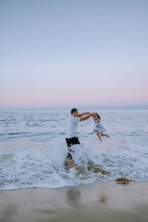 A playful scene of splashing and jumping in ocean waves at sunset on a beach.