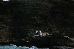 Dark rocky cliffs tower over a scenic beach coastline.