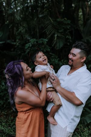 A playful family moment captured in a verdant garden with tropical plants.