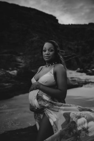 A flowing dress catches the wind during a moody black and white beach photoshoot.