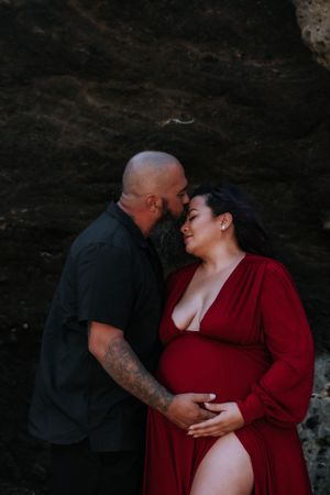 An intimate moment captured between two people against a dark rocky beach backdrop.