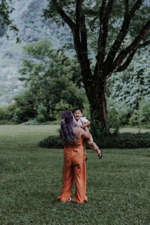 Playful moment captured in a grassy field with trees and mountains in the background.