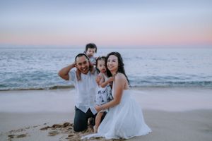A family enjoying tender moments together on a beach during sunset.