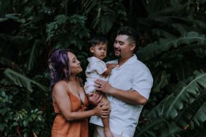 A family shares joyful moments together in a lush tropical garden setting.