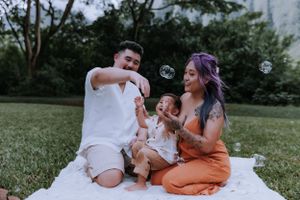 Family enjoying quality time together on a blanket in a park with mountains in background.