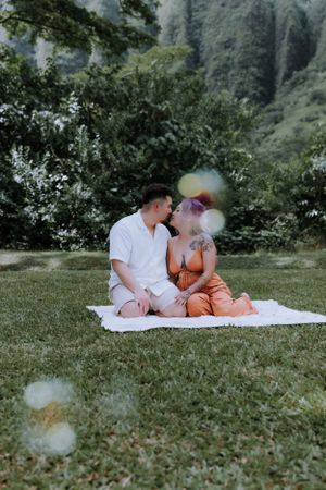 Intimate family moment captured on blanket in park with mountain scenery.