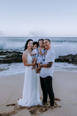 A family sharing loving moments together on a rocky beach at sunset.