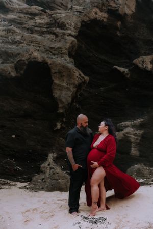 A romantic photoshoot on a secluded beach with dramatic rock formations in the background.