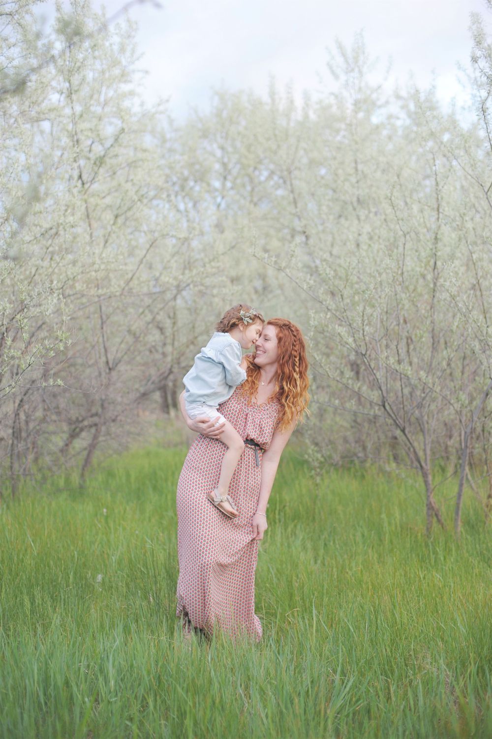 A tender moment between parent and child in a blooming spring orchard in Summerland, B.C.