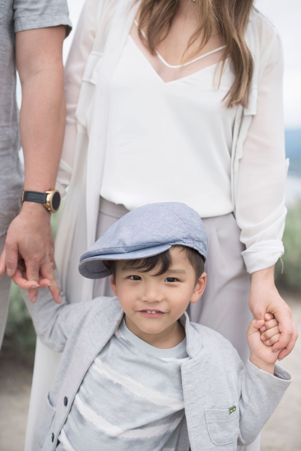 A sweet moment between parents and child in coordinated gray and white outfits at Penticton, B.C.
