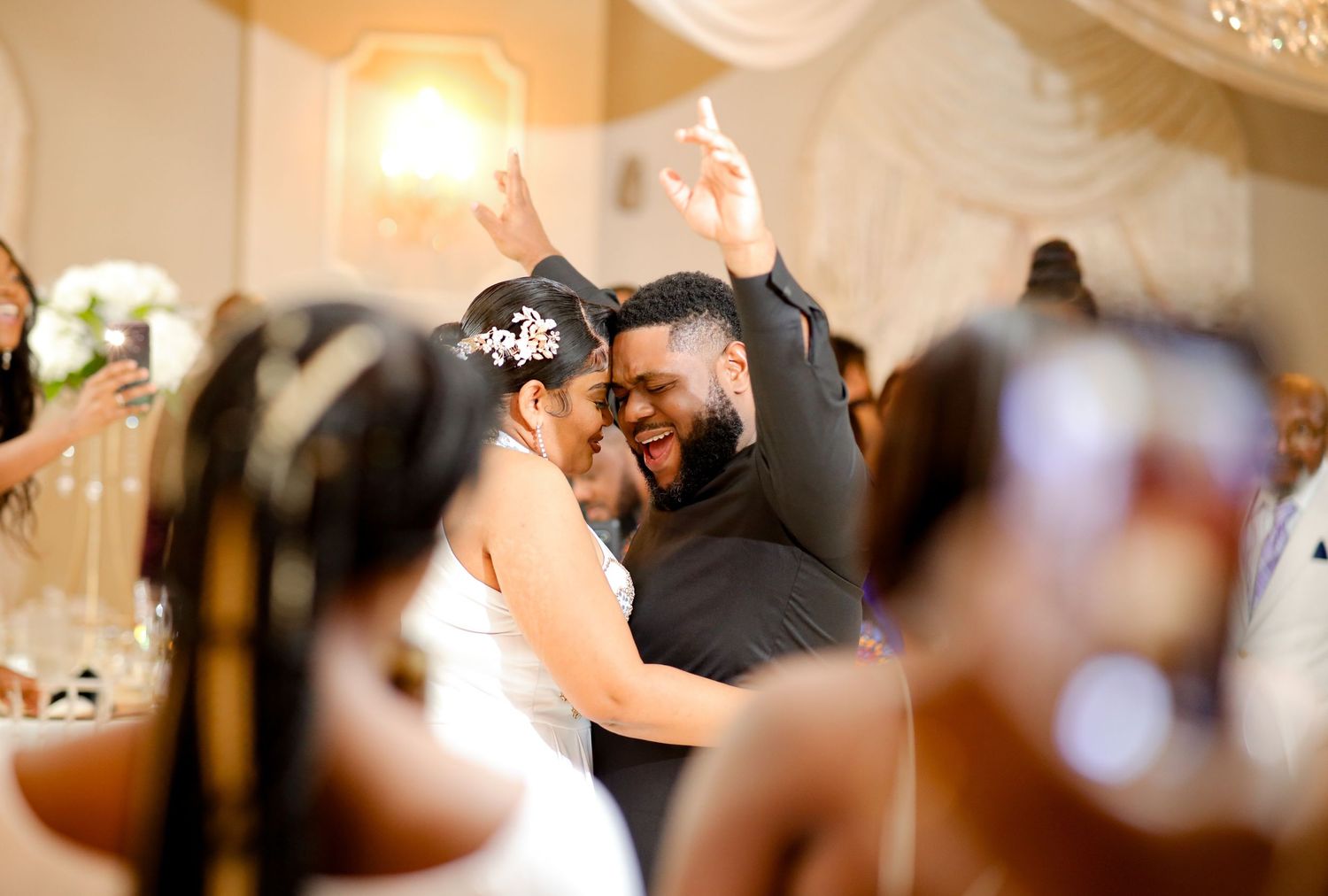 Joyful bride and groom sharing first dance at elegant wedding reception ballroom celebration.