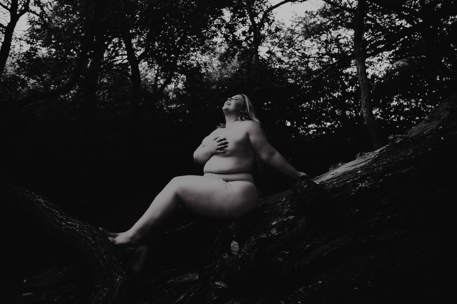 artistic intimates boudoir photo outdoor blonde woman sitting in tree blissful expression embracing herself