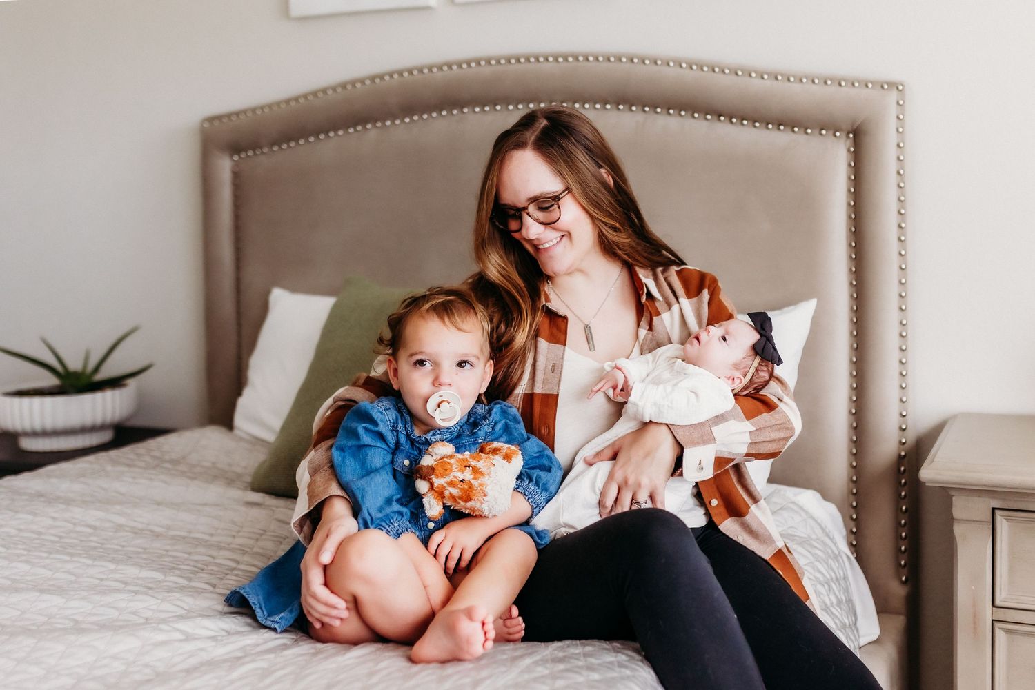 A relaxed family scene on a beige headboard bed with siblings and mother.