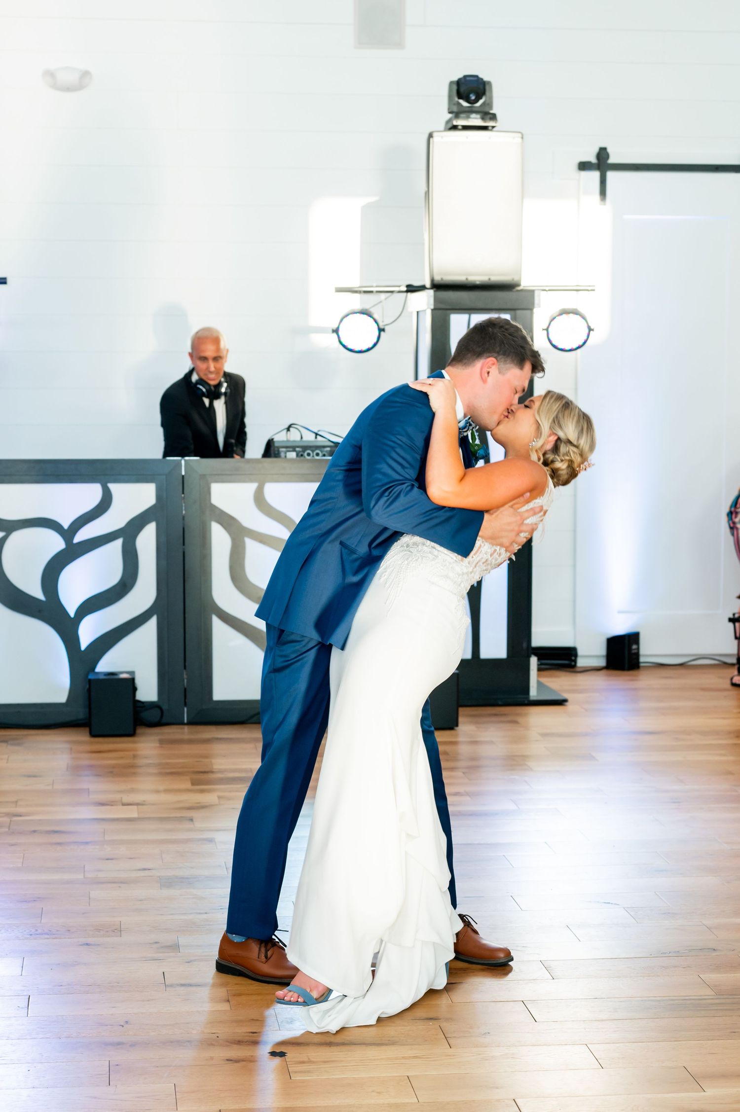 A romantic first dance at a wedding reception shows a couple in navy and white sharing an intimate dip on the dance floor.
