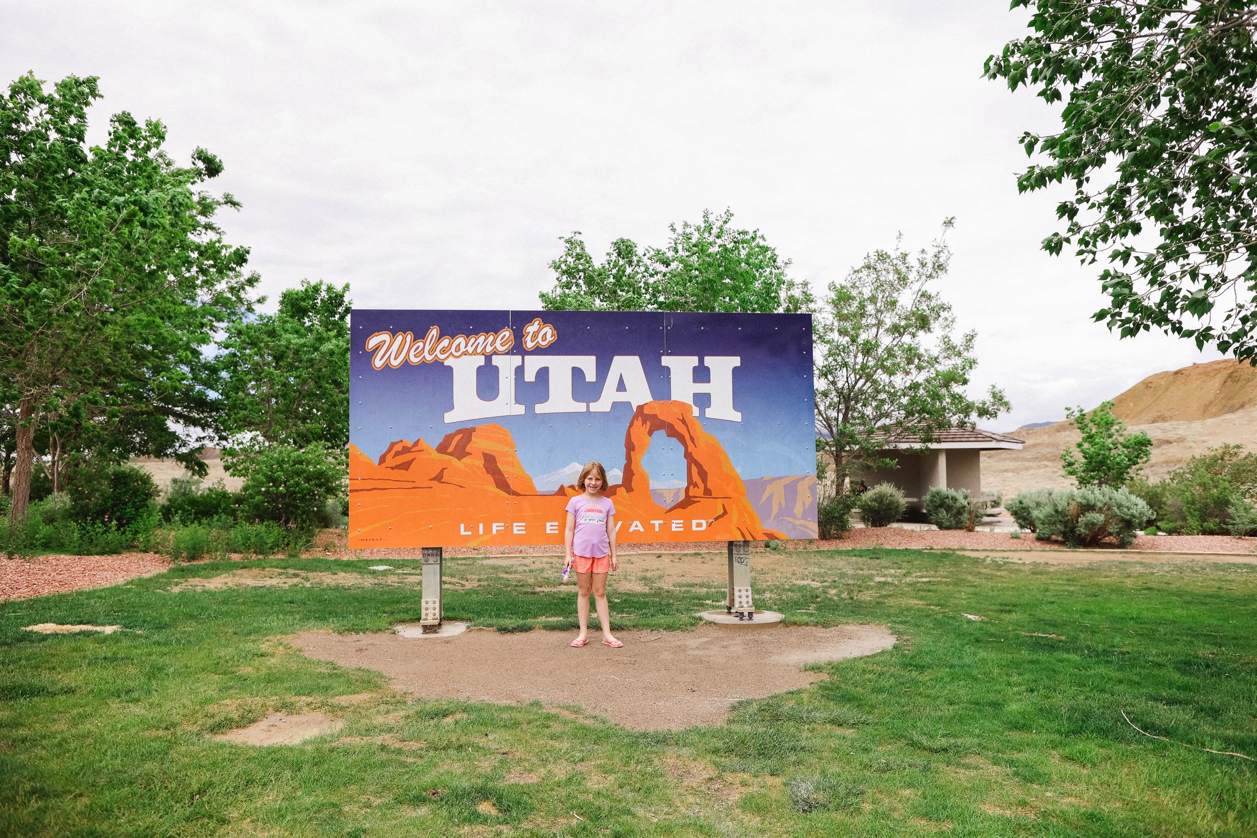 Grassy hillside with a welcome to Utah sign in the background.