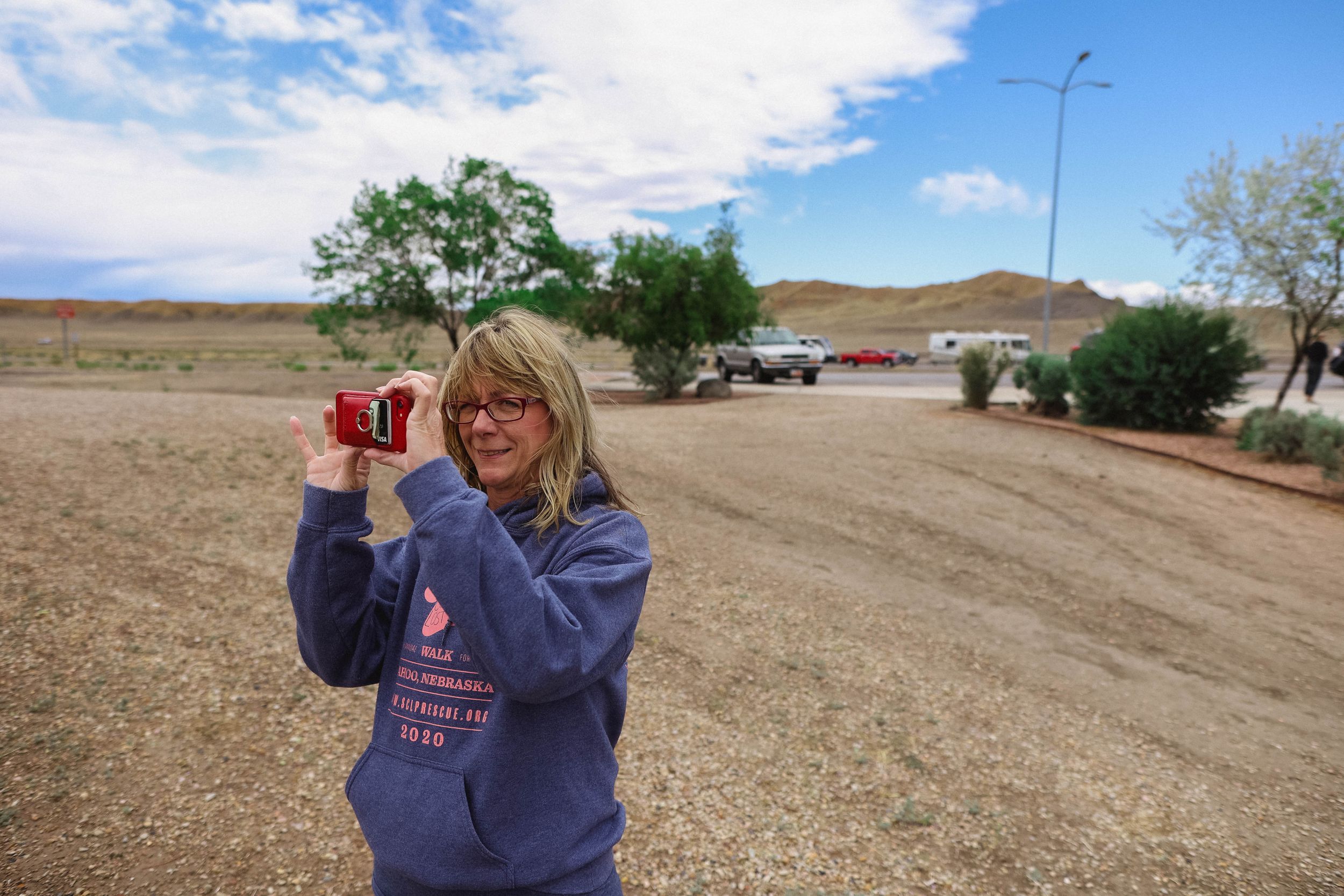 Person exploring a desert landscape with scattered vegetation and hills.