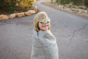 Person wrapped in a cozy gray blanket on an autumn day.
