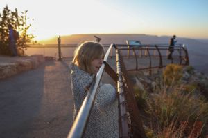 Metal railing along desert viewpoint overlook at sunset with mountains in the distance.