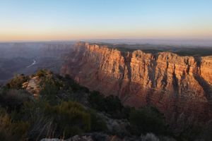 Sweeping panorama of red rock canyon cliffs illuminated by late afternoon sunlight.