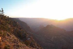 Panoramic vista of mountain ranges and canyons bathed in warm evening sunlight.