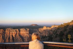 Sweeping view of red rock canyon formations with metal safety barrier at scenic viewpoint.