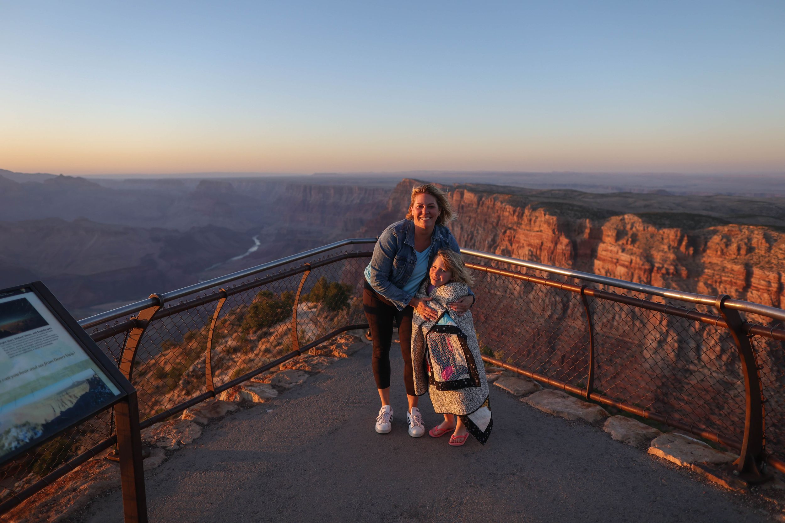 Visitors enjoying sunset views from protected observation area at canyon overlook.