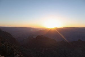 Expansive desert canyon landscape bathed in warm sunset light with layered rock formations.