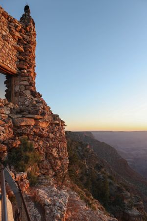 Historic stone watchtower structure at Grand Canyon's edge glowing in late afternoon sunlight.