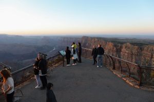 Visitors gather at Grand Canyon observation point to watch the sunset over the vast canyon.