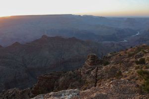 Panoramic view of the Grand Canyon's rugged terrain with winding river visible in the distance.