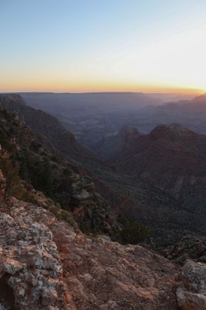 Dramatic sunset view over Grand Canyon's red rock formations and deep valleys.
