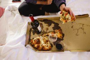 Room service food trays with meals spread across white hotel bedding.